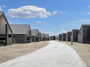 Une rangée de bâtiments modernes aux couleurs sombres, avec un chemin de gravier qui les traverse.