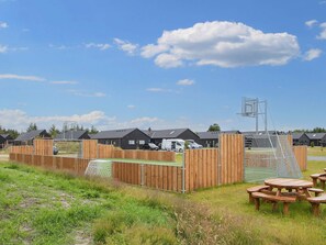 Un terrain de camping doté de cabanes en bois, de tables de pique-nique et d’un terrain de basketball.