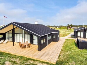 A modern house with a large deck, a dining area, and a view of the surrounding landscape. - 5 Star Holiday Home in Lokken (Lokken)