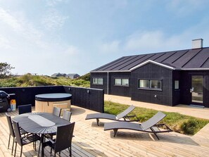 A modern house with a deck, a hot tub, and outdoor seating.
