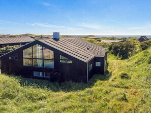 A modern house with a sloped roof, large windows, and a chimney. - 5 Star Holiday Home in Lokken (Lokken)