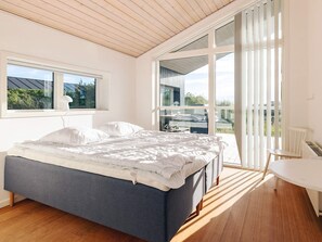 A bedroom with a bed, a window, a balcony, and a table. - 5 Star Holiday Home in Lokken (Lokken)