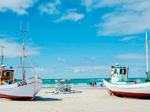 Two boats on a sandy beach with the ocean in the background.