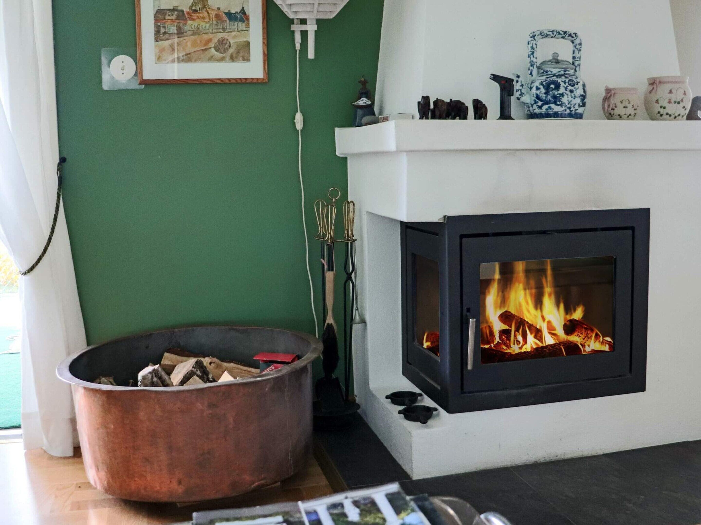 Ein Wohnzimmer mit Kamin, einer grünen Wand und einem Kupferkamin.