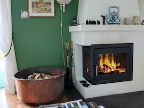 A room with a fireplace, a large copper pot, and a framed picture on the wall.