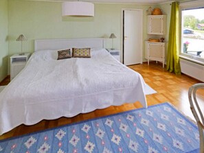 Een slaapkamer met een bed, twee nachtkastjes, een raam met gordijnen en een deur.