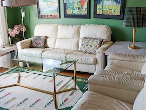 Un salon avec un canapé, une table basse en verre et un tapis à motifs.