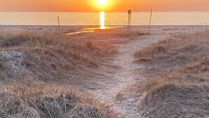 A beach path leading to the ocean with a sunset in the background. - 7 Person Holiday Home in Skummeslovsstrand (Skummesloevsstrand)