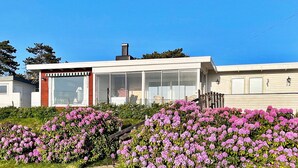 A modern two-story house with a large glass windowed front porch, surrounded by flowering shrubs. - 7 Person Holiday Home in Skummeslovsstrand (Skummesloevsstrand)