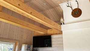 Una habitación con vigas de madera, cabeza de venado montada y chimenea.