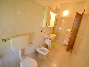 Une salle de bain comprenant des toilettes, un bidet, un lavabo et un miroir au-dessus du lavabo.
