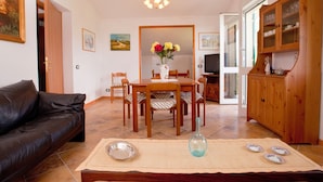 A living room with a sofa, a dining table with chairs, a TV, and a cabinet. - Cottage in Sesta Godano Near the Sea (Sesta Godano)