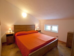 Une chambre à coucher avec un lit en bois, deux tables de chevet avec des lampes, une fenêtre et une armoire.