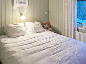 A bed with white bedding, a wall-mounted light, a framed picture, and a window with curtains. - 5 Star Holiday Home in Haro (Harö)
