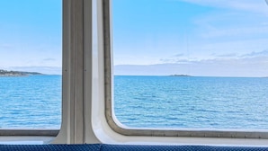 A view from a ship's window with a clear blue sea and a distant island. - 5 Star Holiday Home in Haro (Harö)