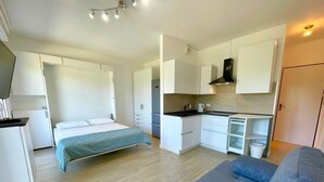 A compact room with a bed, kitchenette, and a sofa. - Apartment Porto Santa Margherita by Beach (Caorle)