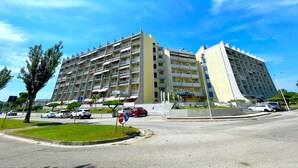 A multi-story hotel with balconies, a parking area, and a clear sky. - Apartment Porto Santa Margherita by Beach (Caorle)