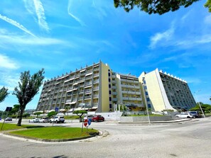 A multi-story hotel with balconies, a parking area, and a clear sky. - Apartment Porto Santa Margherita by Beach (Caorle)