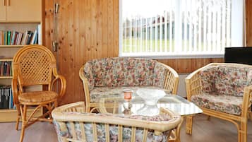 Una habitación con muebles de mimbre, una estantería y una ventana con persianas.