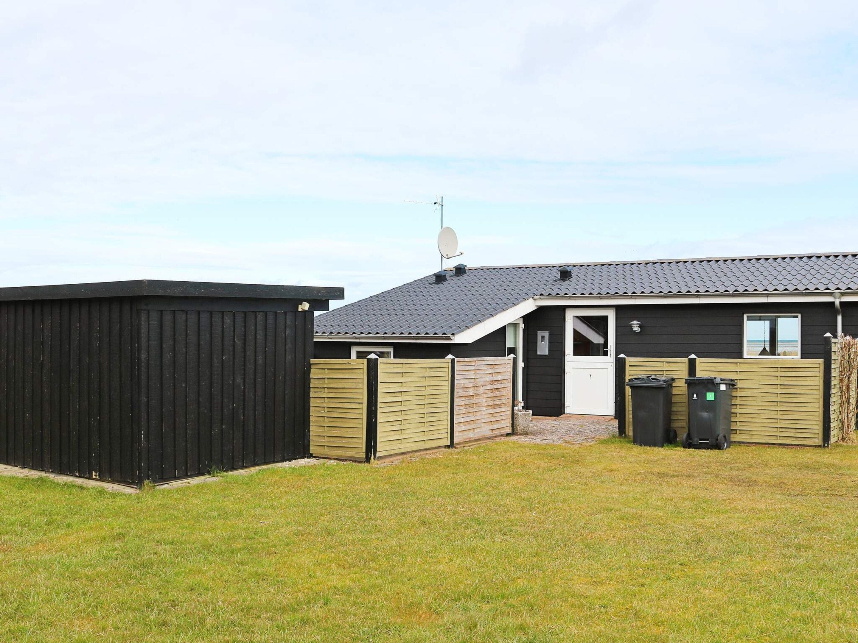 A single-story building with a dark exterior, a tiled roof, and a small front porch.