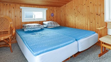 Una habitación con paneles de madera, una cama, un ventanal y una silla.