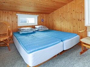 Een kamer met houten lambrisering, een bed, een raam en een stoel.