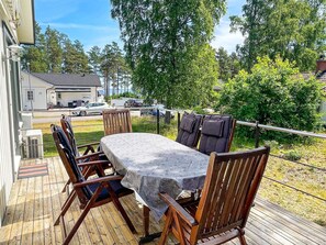A wooden deck with a table and chairs, overlooking a residential area with houses and parked cars. - 5 Person Holiday Home in 38472 (Timmernabben)