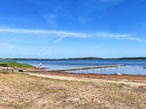 A lakeside view with a dock extending into the water, a lifebuoy on the dock, and a grassy area in the foreground. - 5 Person Holiday Home in 38472 (Timmernabben)