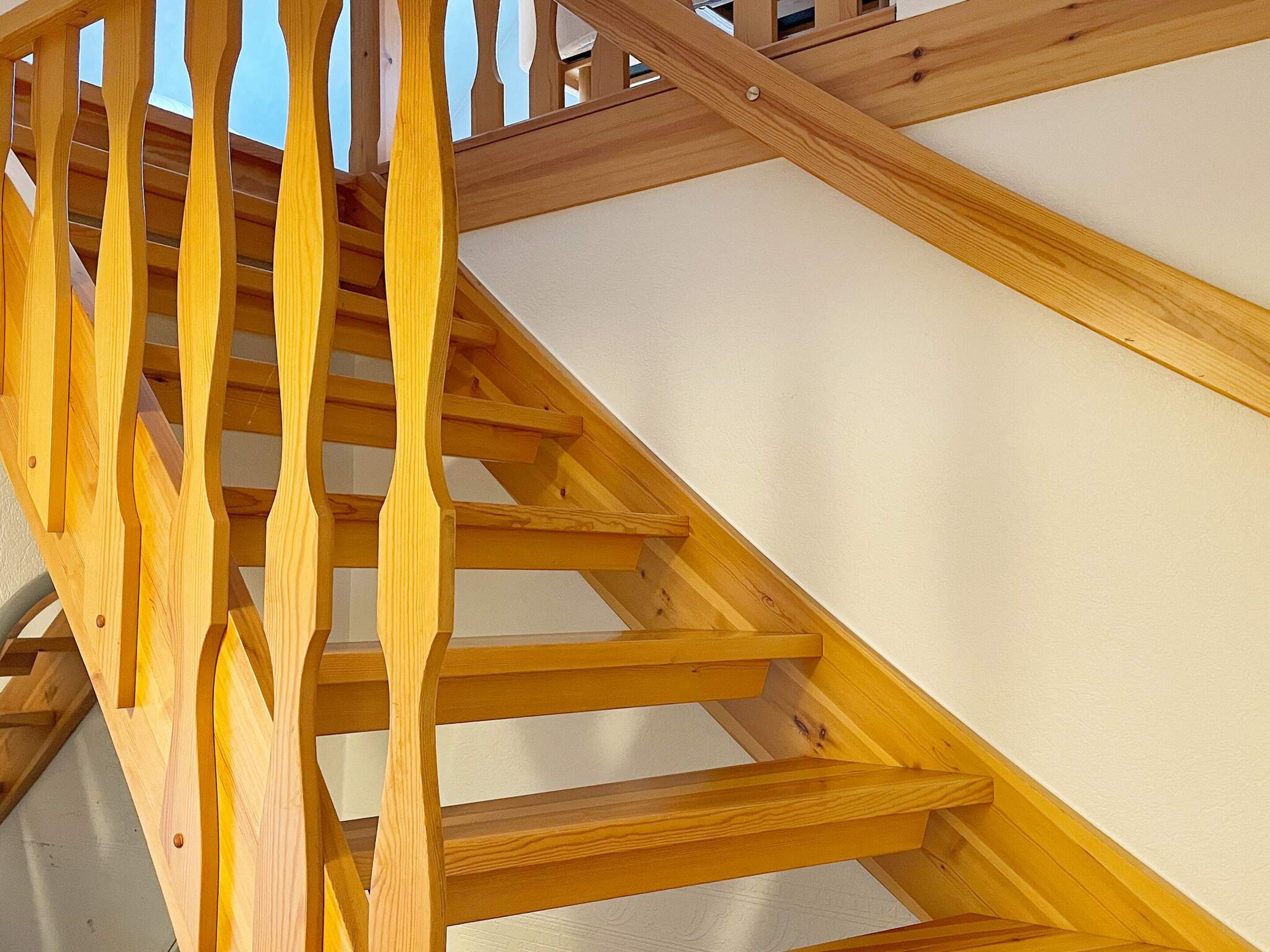 A wooden staircase with a handrail and steps leading to an upper level.