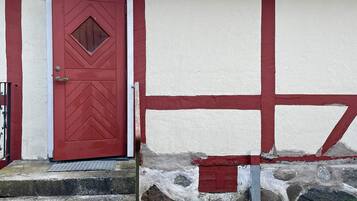 A red door with a diamond-shaped window and a white wall with red trim.