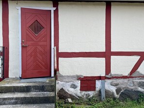 A red door with a diamond-shaped window and a white wall with red trim. - 4 Person Holiday Home in Lovestad (Lövestad)