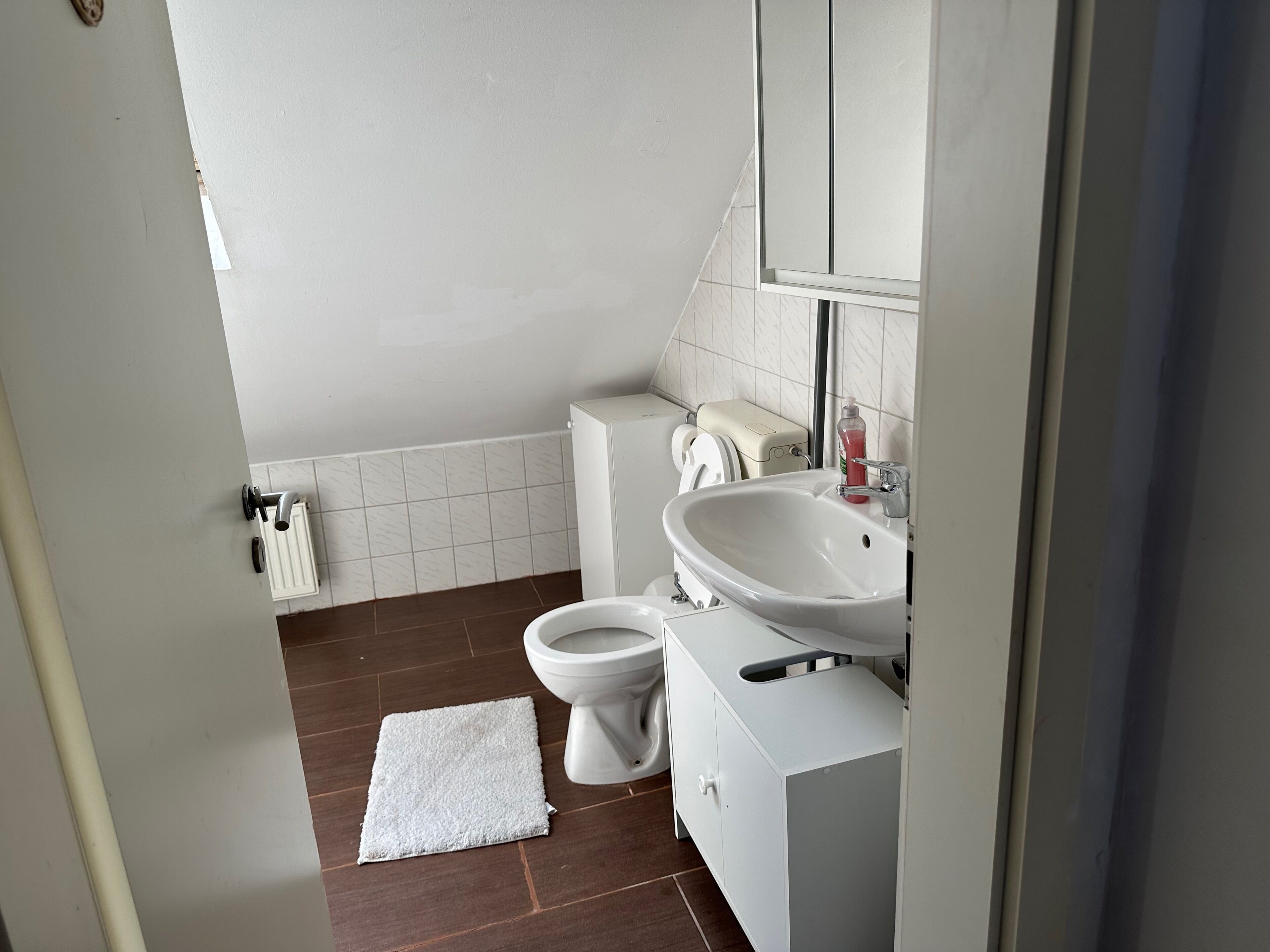 A modern bathroom with a toilet, sink, and mirror.