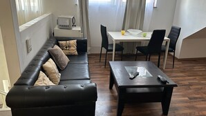 Ett vardagsrum med en svart lädersoffa, ett soffbord i trä och ett matbord med stolar.