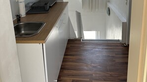 Ett kompakt kök med en diskho, en arbetsbänk och ett fönster med gardiner.