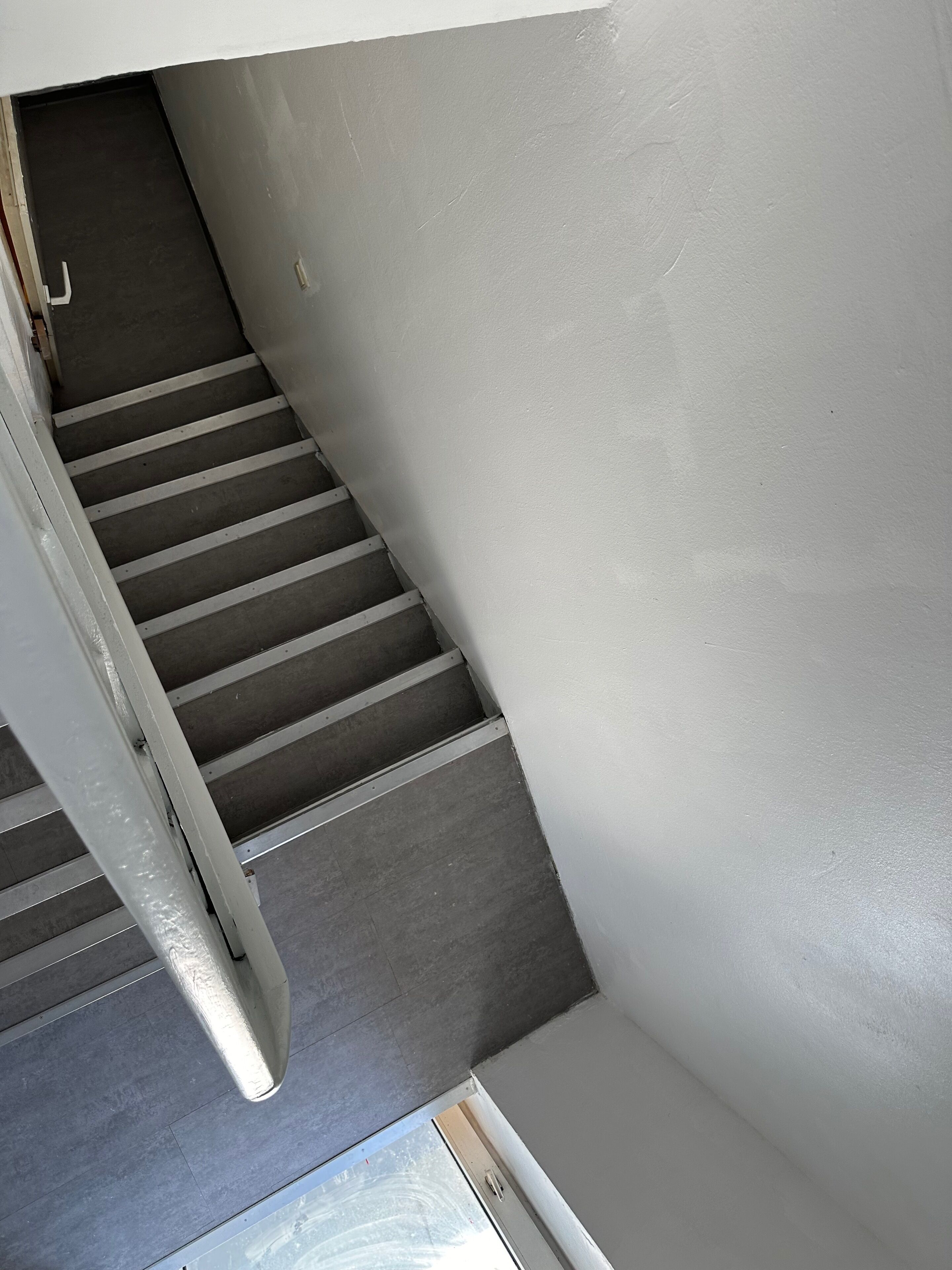 A staircase with a metal handrail and a white wall.