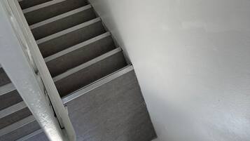 A staircase with a metal handrail and a white wall.