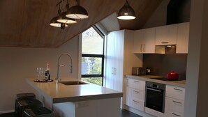 A modern kitchen with a large island, white cabinetry, and a built-in oven. - Royale on Cheese (Castle Hill)