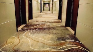 Un couloir avec un tapis à motifs et des portes en bois.