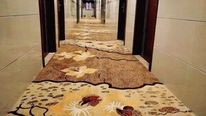 Un couloir avec un tapis à motifs et des murs recouverts de carreaux.