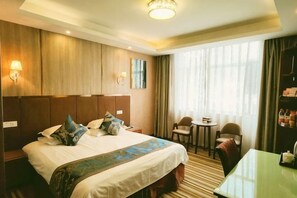 Quarto de hotel com uma cama grande, uma mesa pequena, uma cadeira, uma escrivaninha e uma janela com cortinas.