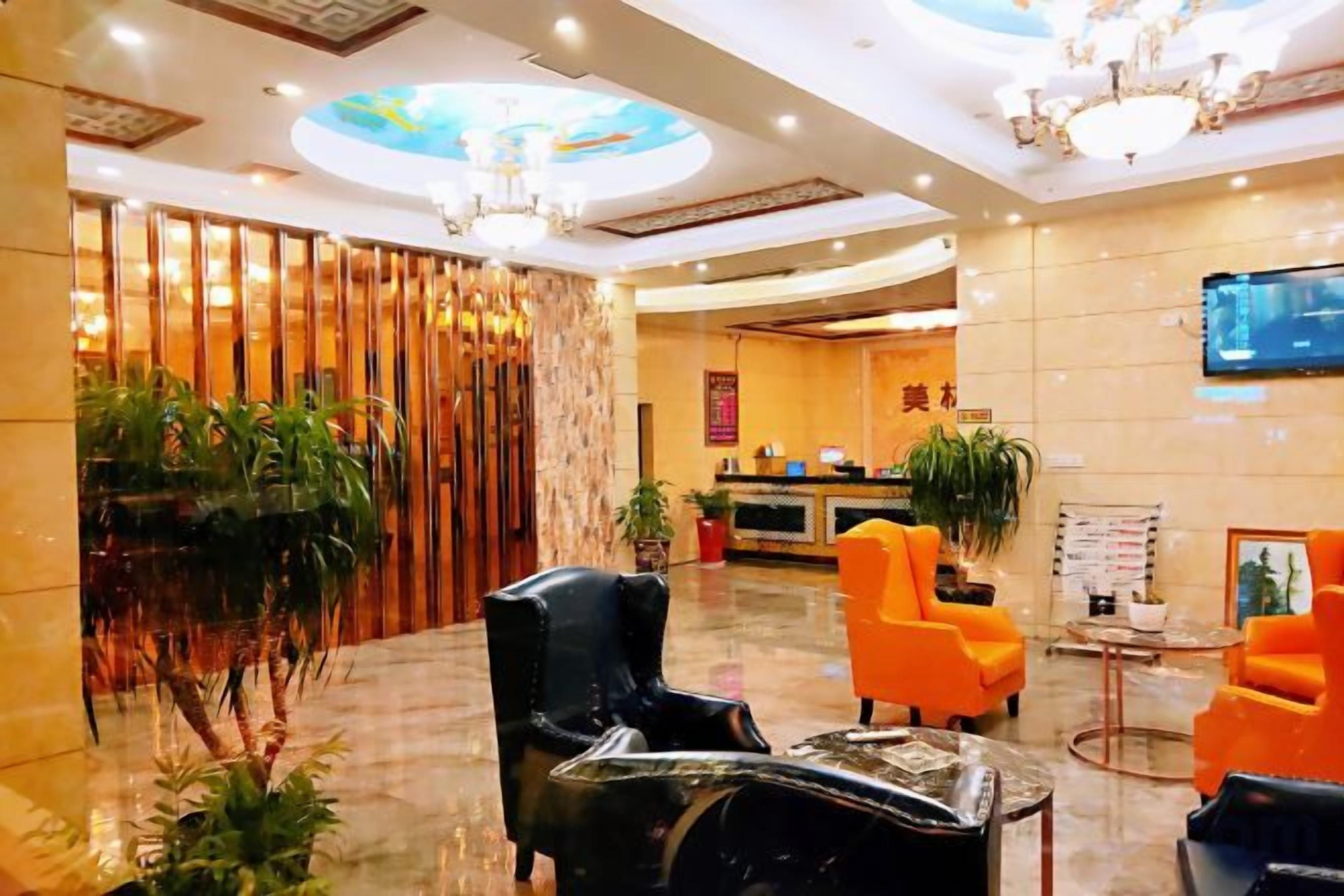 A hotel lobby with a reception desk, seating area, and a chandelier.