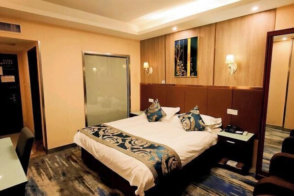 Habitación de hotel con cama, mesita de noche, lámpara y espejo.