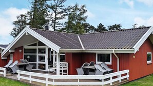 Un edificio rosso con veranda coperta, ringhiere bianche e mobili da esterno.