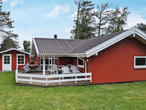 A red building with a covered patio area featuring outdoor furniture. - 6 Person Holiday Home in Otterup (Otterup)