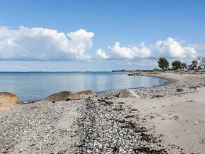 A pebbled beach with large rocks, a calm sea, and a clear sky. - 6 Person Holiday Home in Otterup (Otterup)
