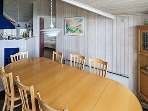 A dining area with a wooden table and chairs, a hanging pendant light, and a painting on the wall. - 6 Person Holiday Home in Otterup (Otterup)