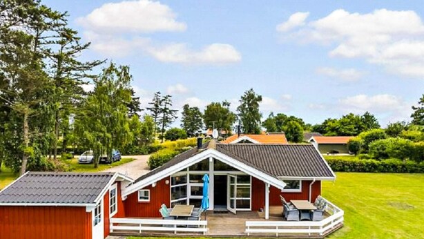A red house with a white porch and a covered patio area. - 6 Person Holiday Home in Otterup (Otterup)