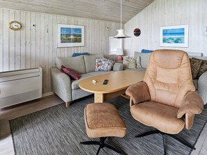 A room with a sofa, armchair, ottoman, and a table with a remote control. - 6 Person Holiday Home in Otterup (Otterup)
