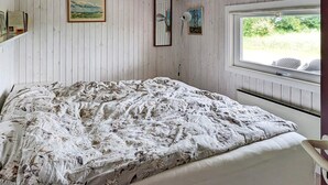 A bedroom with a bed, a window with a view of greenery, and two framed pictures on the wall. - 6 Person Holiday Home in Otterup (Otterup)