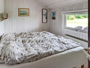 A bedroom with a bed, a window with a view of greenery, and two framed pictures on the wall. - 6 Person Holiday Home in Otterup (Otterup)
